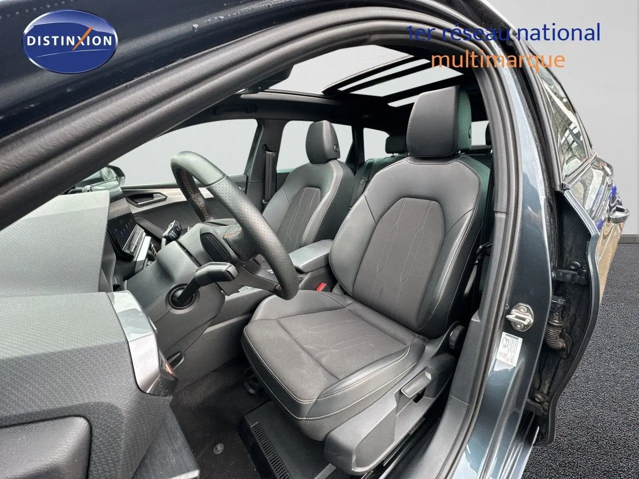 Vue intérieure côté conducteur de la CUPRA LEON ST 2024 gris magnetic metal avec sièges en cuir noir et toit panoramique.