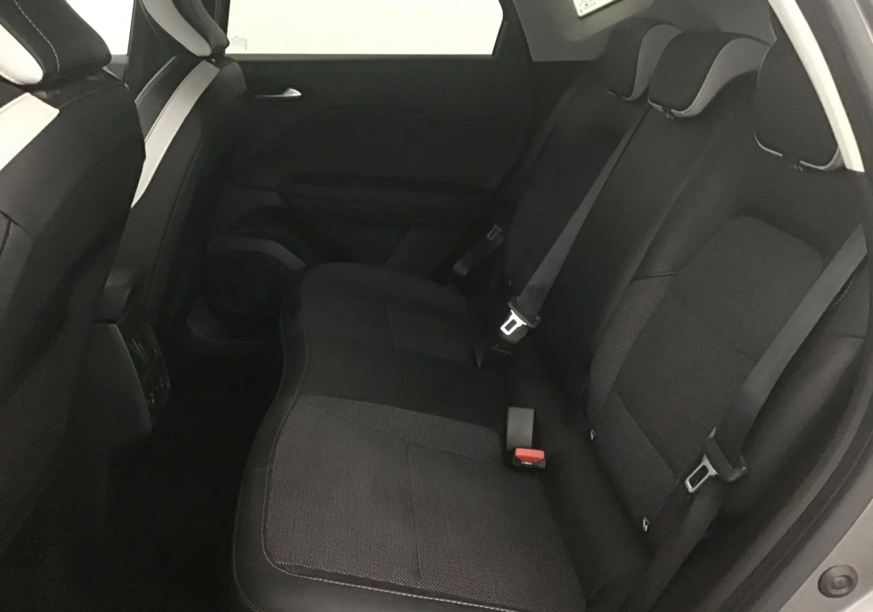 Vue latérale droite de l'habitacle arrière du Renault Captur 2024 avec sièges noirs en tissu et cuir.