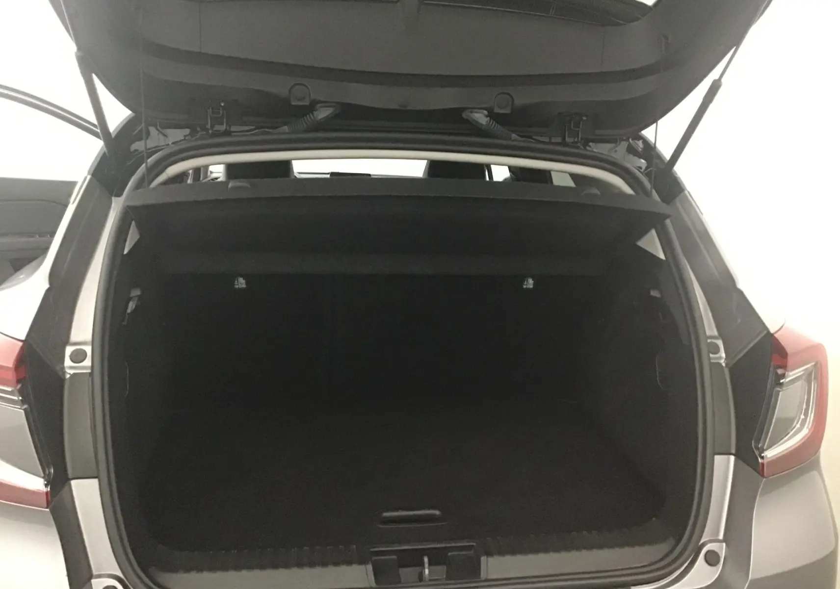 Coffre ouvert en vue arrière d'un Renault Captur gris cassiopée et noir, montrant l'espace de chargement vide.