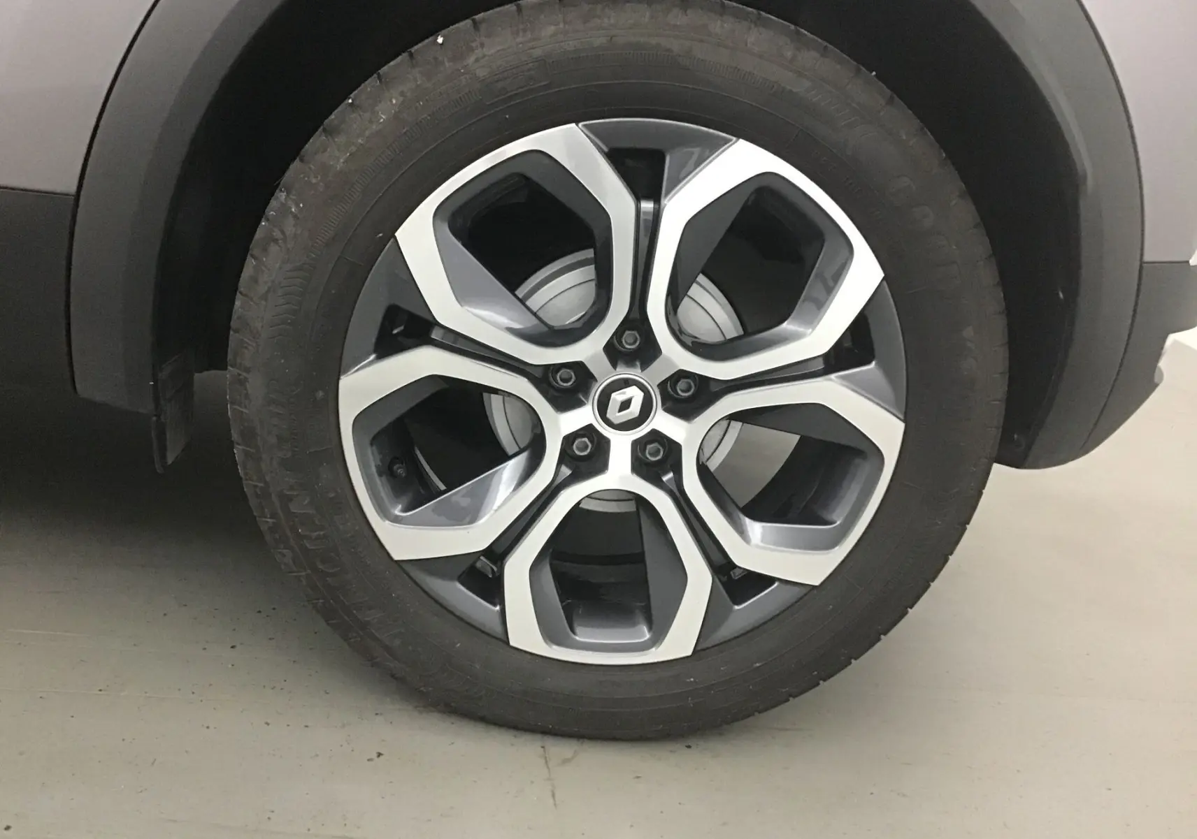 Gros plan sur la roue avant gauche du Renault Captur 2024 gris Cassiopée avec jante alliage 18 pouces au design moderne.