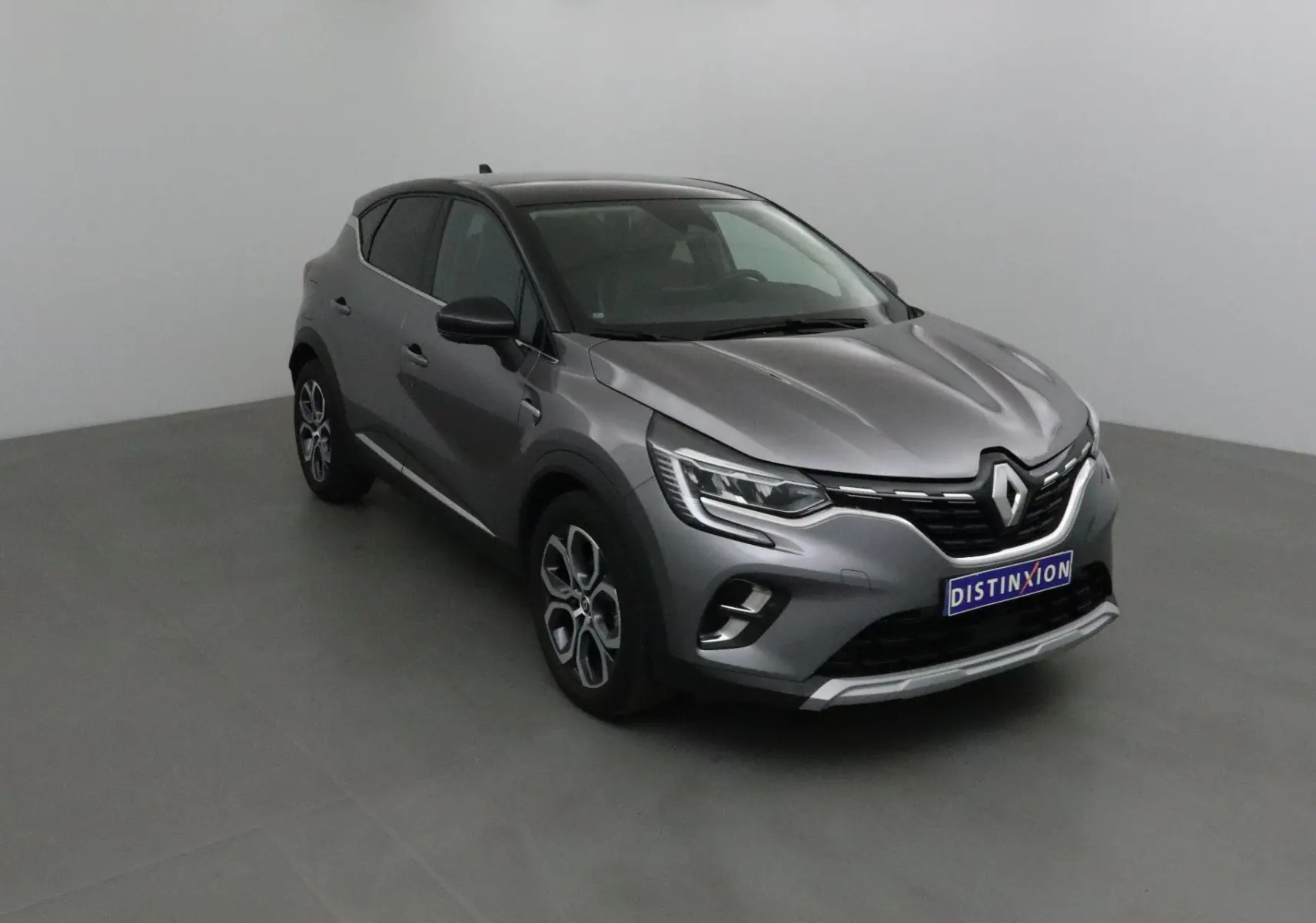 Renault Captur 2024 gris Cassiopée et noir, vue 3/4 avant avec jantes 18 pouces et calandre distinctive.