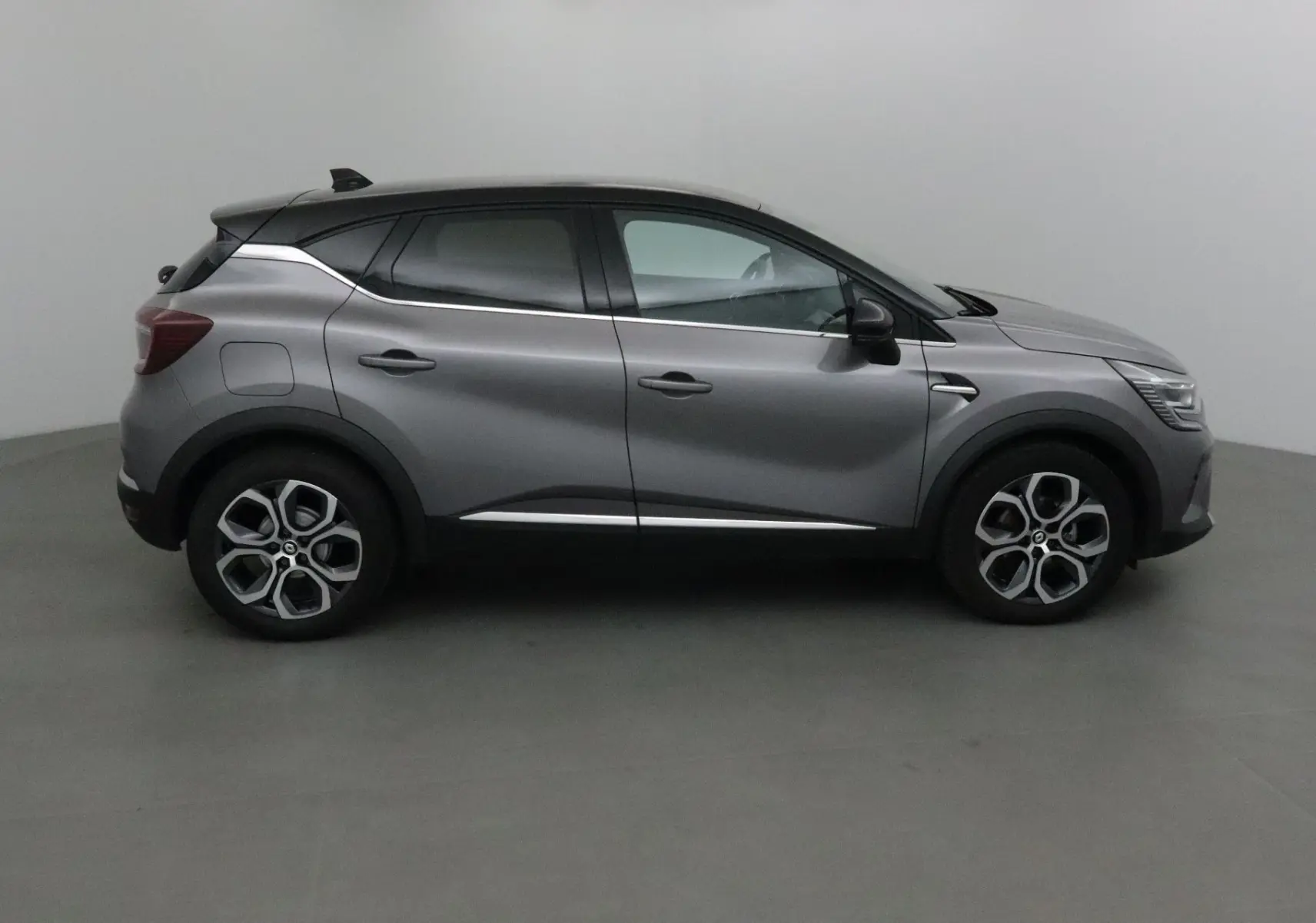 Profil droit du Renault Captur 2024 gris cassiopée avec toit noir et jantes alliage 18 pouces.