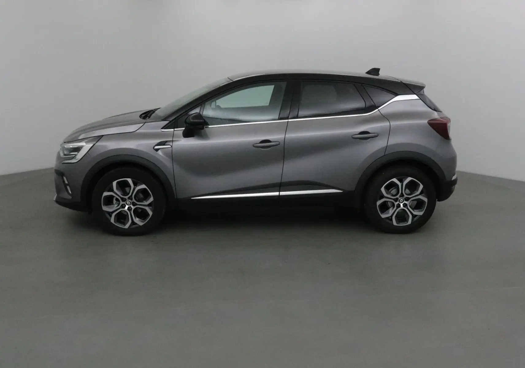 Profil côté gauche du Renault Captur 2024 gris Cassiopée avec toit noir et jantes alliage 18 pouces.