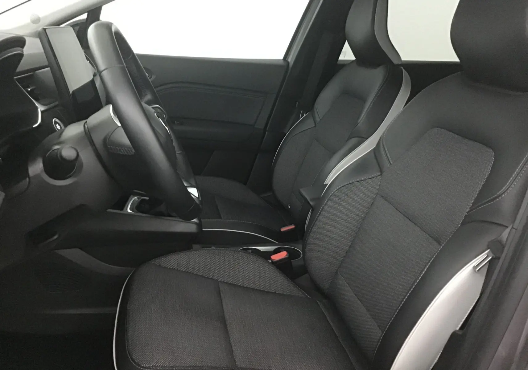 Intérieur avant du Renault Captur 2024, sièges noirs avec surpiqûres grises et tableau de bord moderne côté conducteur.