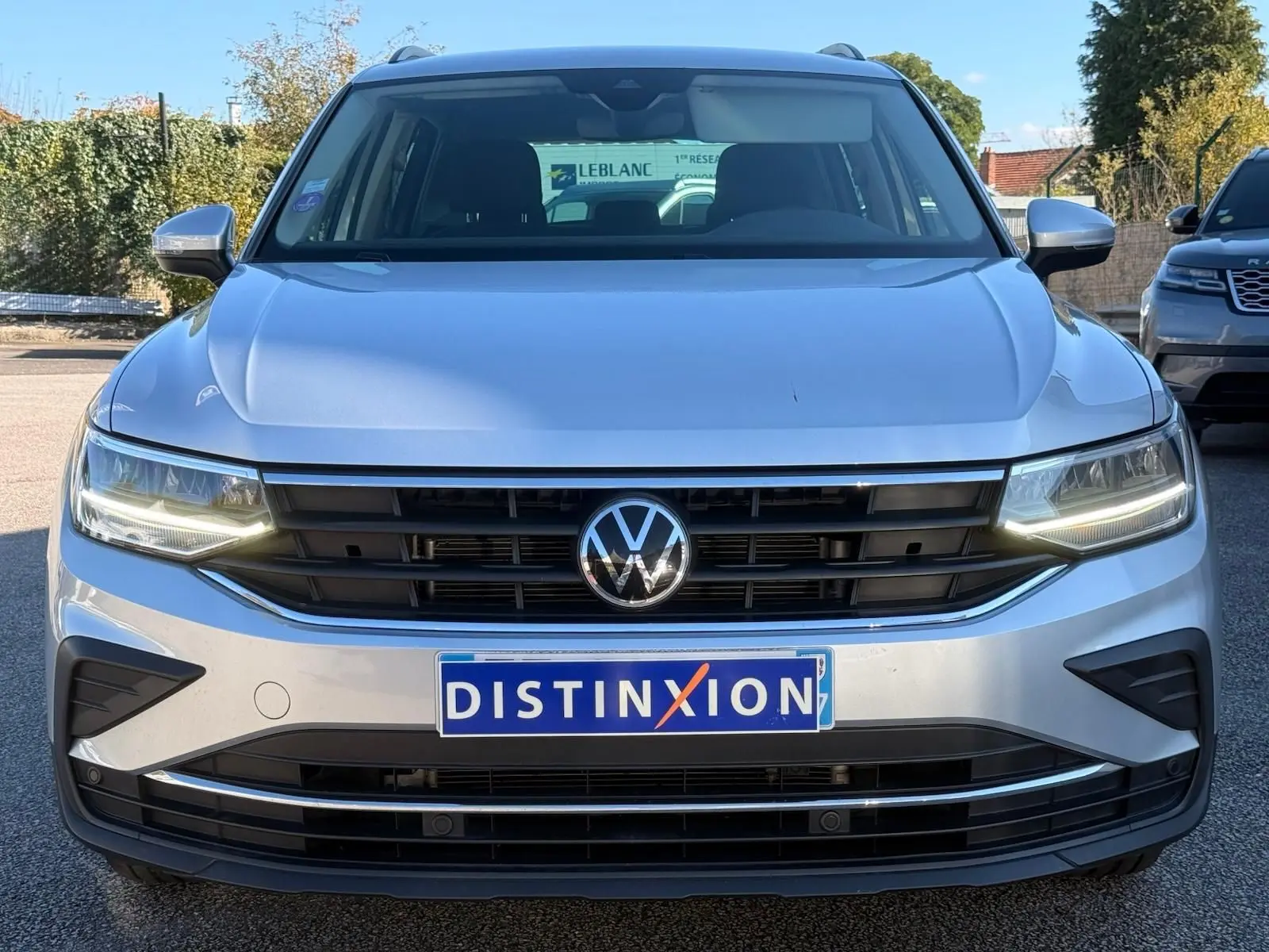 Vue de face d'un Volkswagen Tiguan 1.5 TSI 150CH LIFE DSG7 en reflet argent avec calandre noire et phares LED allumés.