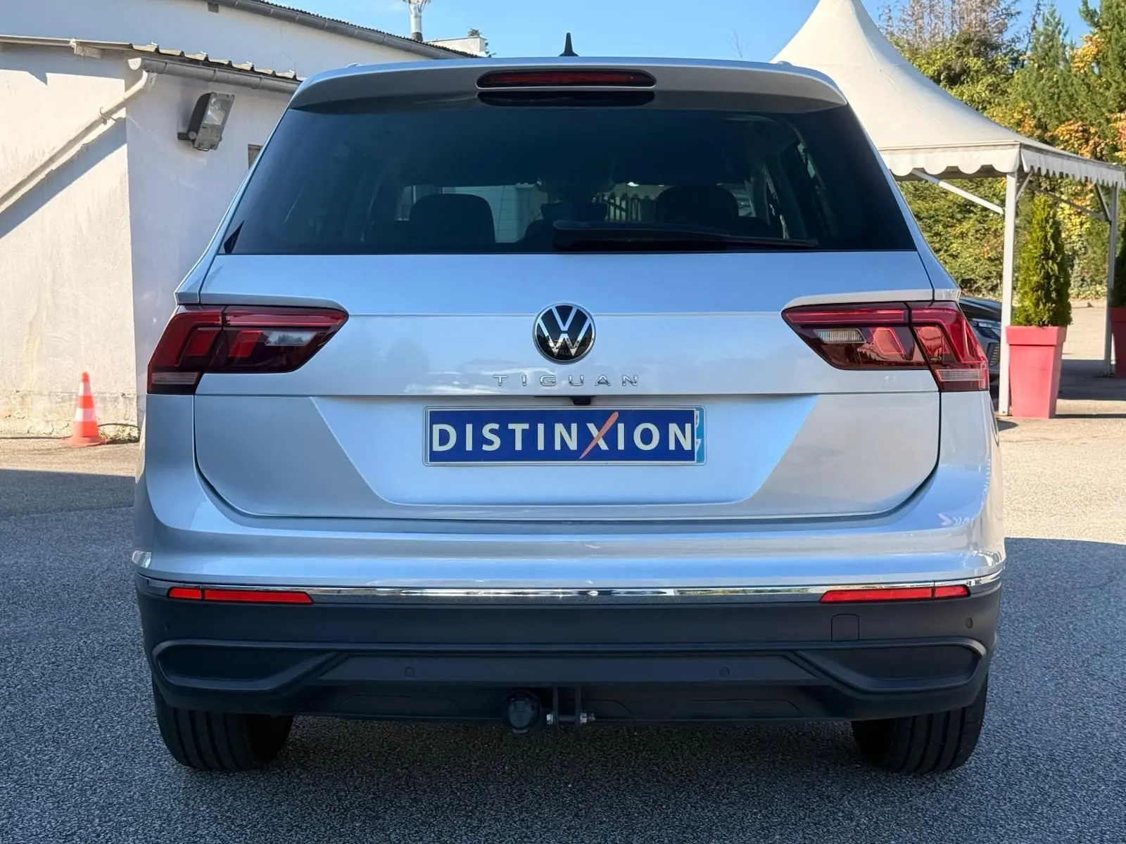 Vue arrière d'un Volkswagen Tiguan 1.5 TSI 150CH LIFE DSG7 en reflet argent avec attelage et feux LED.
