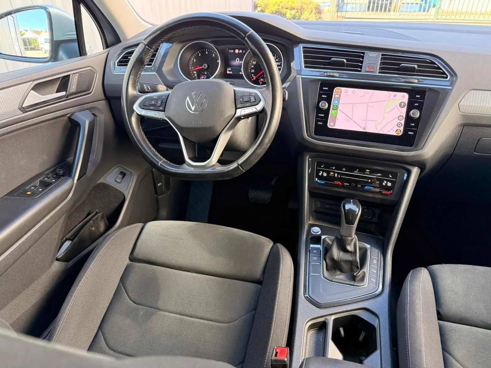 Vue intérieure du Volkswagen Tiguan 2021 côté conducteur, tableau de bord noir avec écran tactile et levier de boîte automatique.