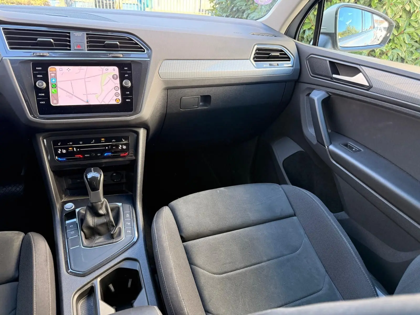 Vue intérieure côté passager du Volkswagen Tiguan 2021, mettant en valeur la console centrale et l'écran tactile.