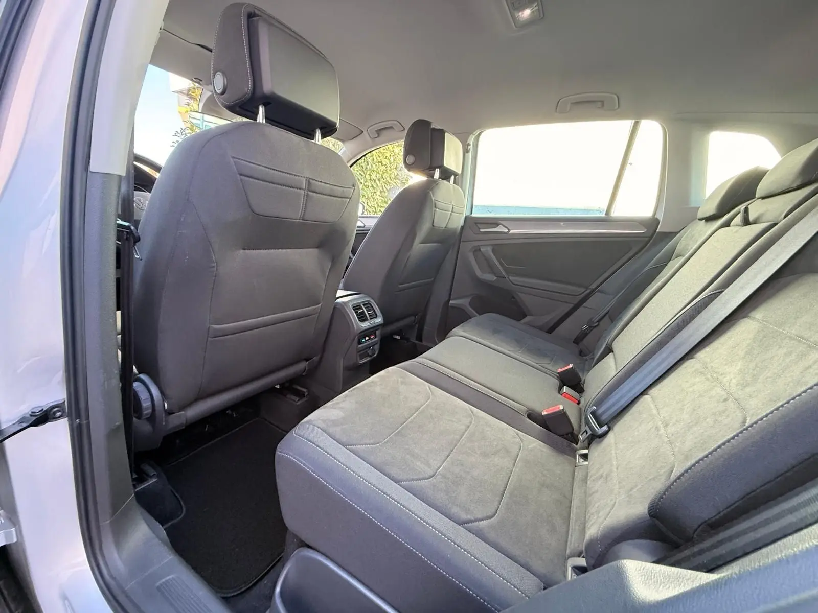Vue intérieure arrière du Volkswagen Tiguan 2021 en reflet argent, sièges arrière en tissu gris avec ceintures de sécurité visibles.