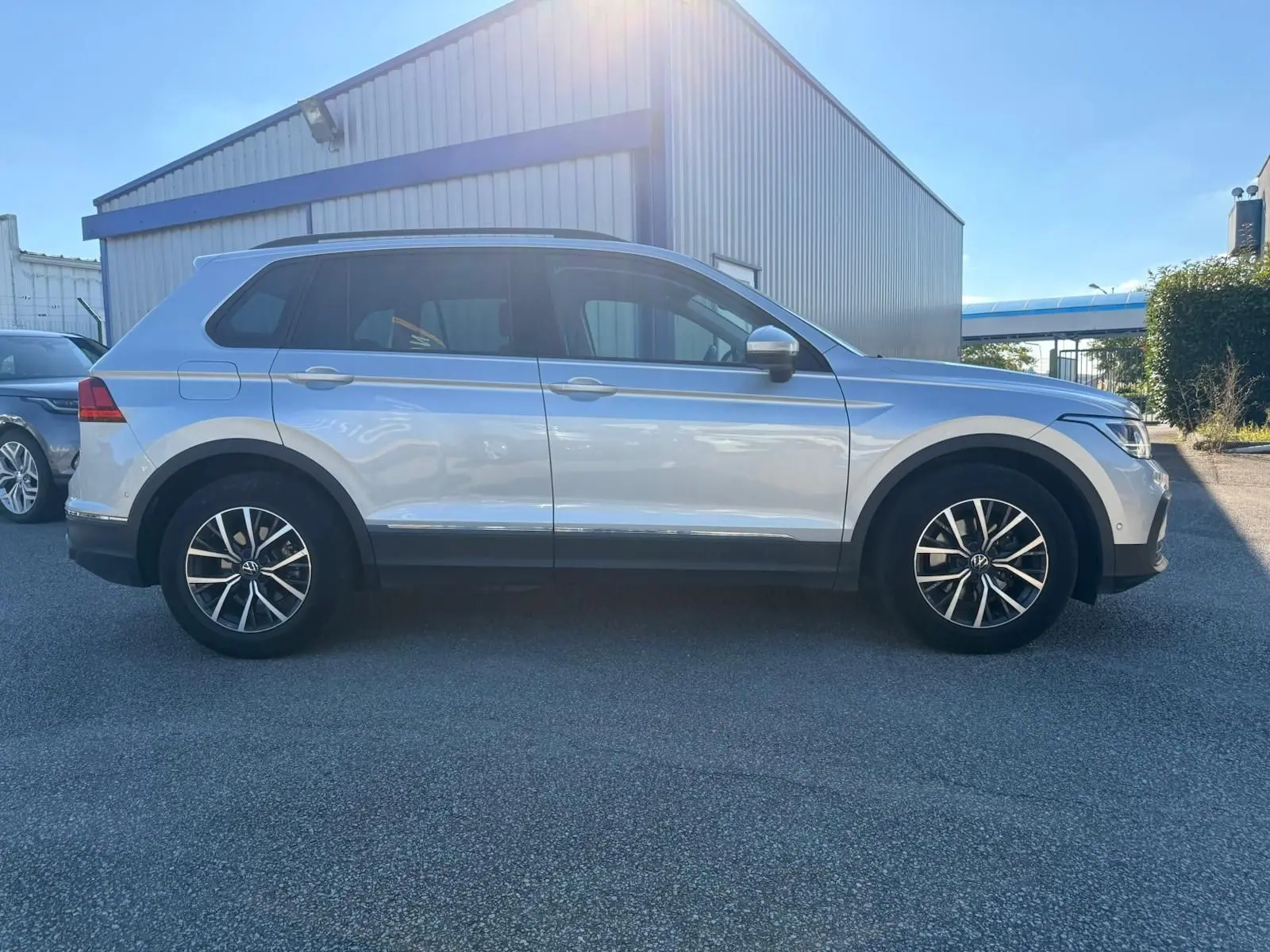 Volkswagen Tiguan 1.5 TSI 150CH LIFE DSG7 en reflet argent vu de profil côté gauche, avec jantes alliage et vitres teintées.