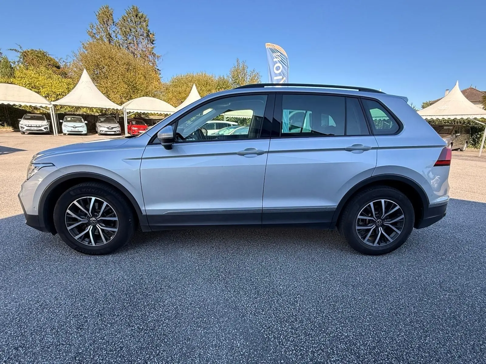 Profil côté gauche d'un Volkswagen Tiguan 1.5 TSI 150CH LIFE DSG7 en reflet argent avec jantes alliage noires.