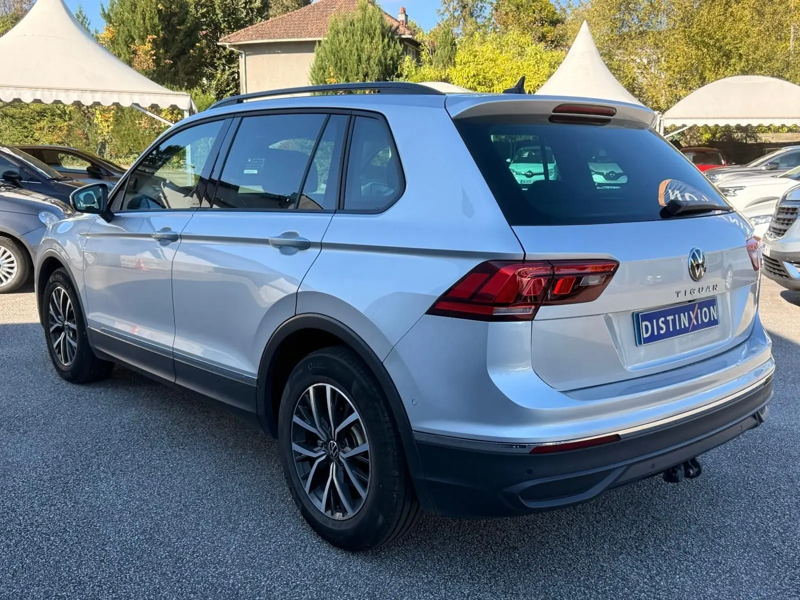 Volkswagen Tiguan reflet argent vu de trois quarts arrière droit, avec jantes alliage et hayon fermé sur parking.