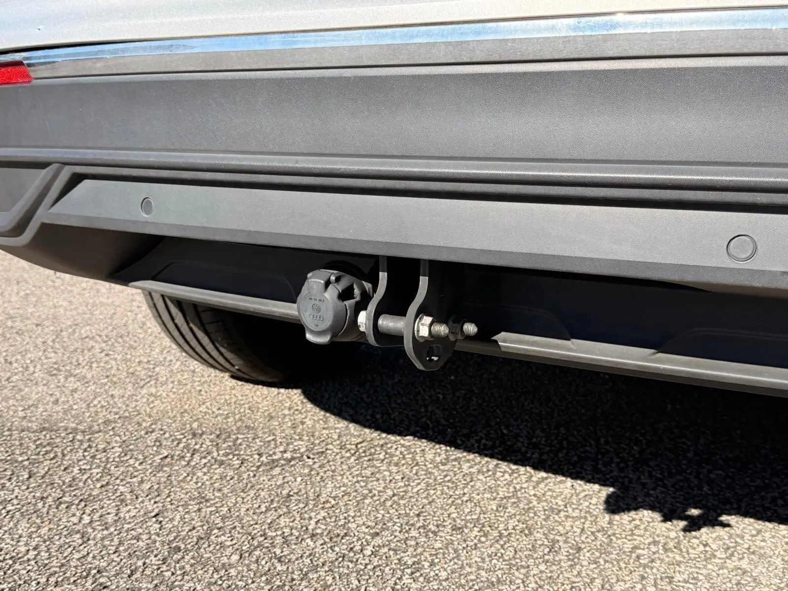 Gros plan sur l'attelage arrière du Volkswagen Tiguan 1.5 TSI 150ch Life DSG7 en reflet argent, avec prise électrique visible.