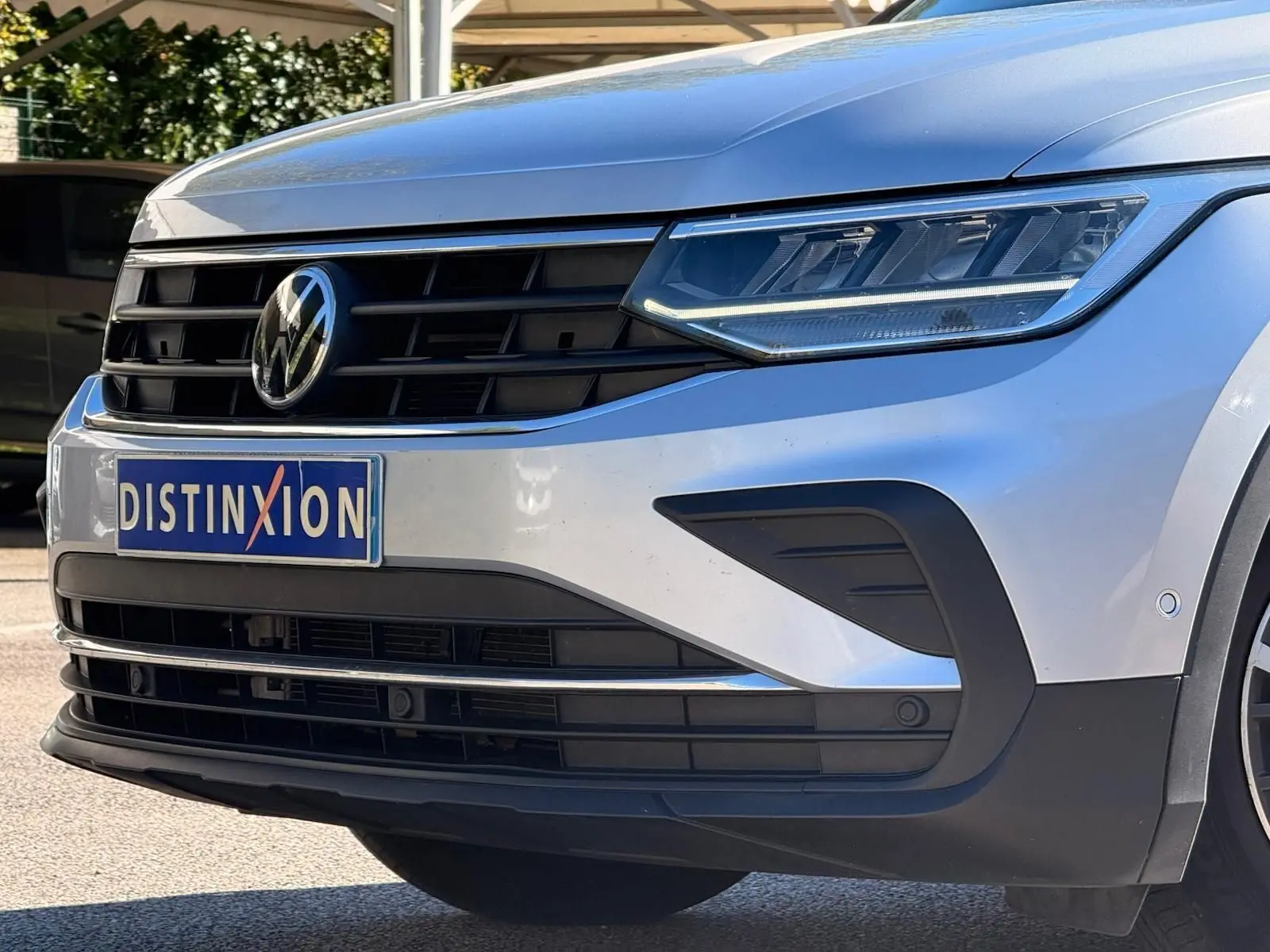 Gros plan sur l'avant droit d'un Volkswagen Tiguan 2021 reflet argent avec calandre noire et phares LED distinctifs.