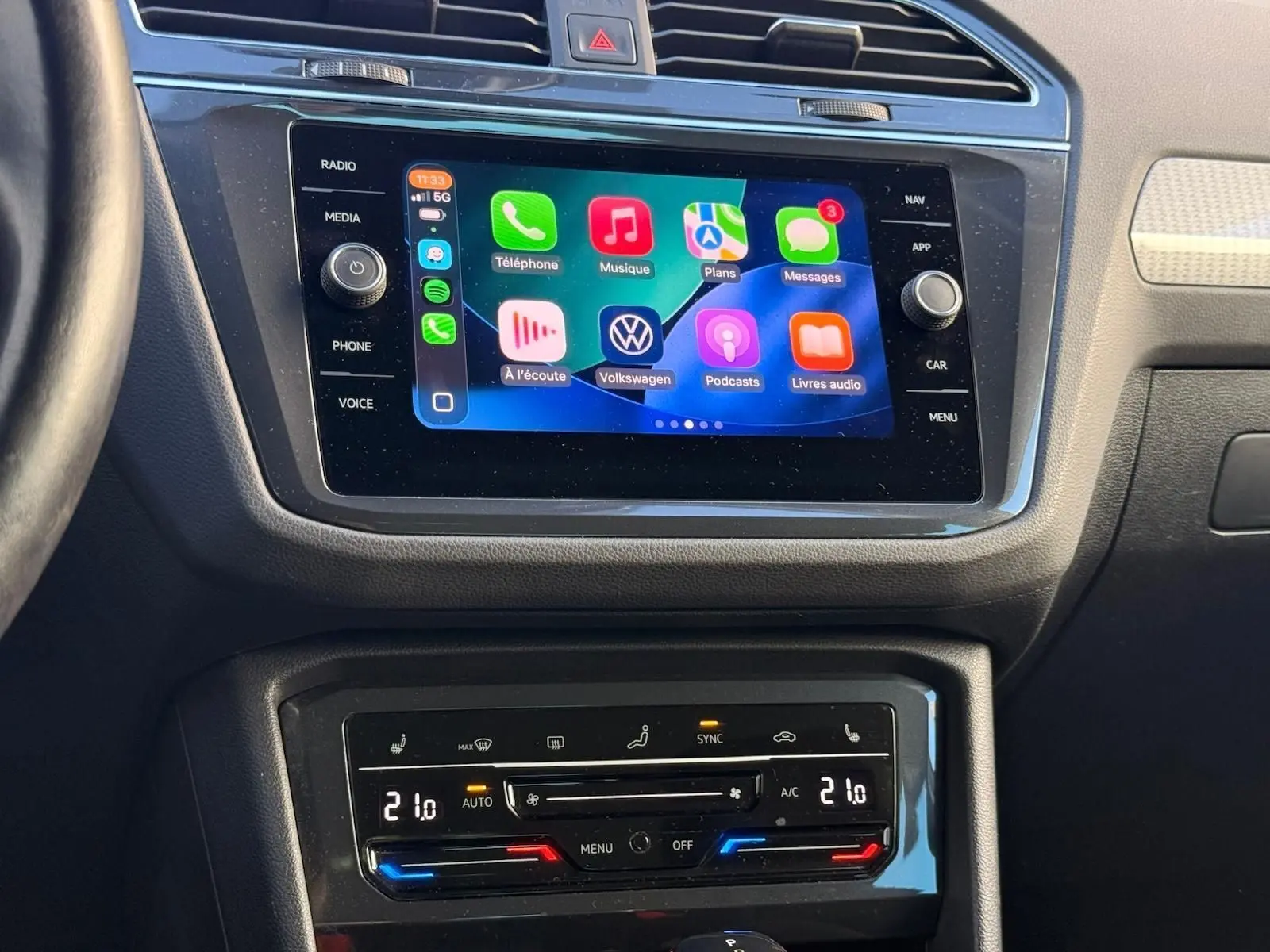 Tableau de bord du Volkswagen Tiguan 1.5 TSI 150CH Life 2021, écran tactile et commandes climatisation visibles.