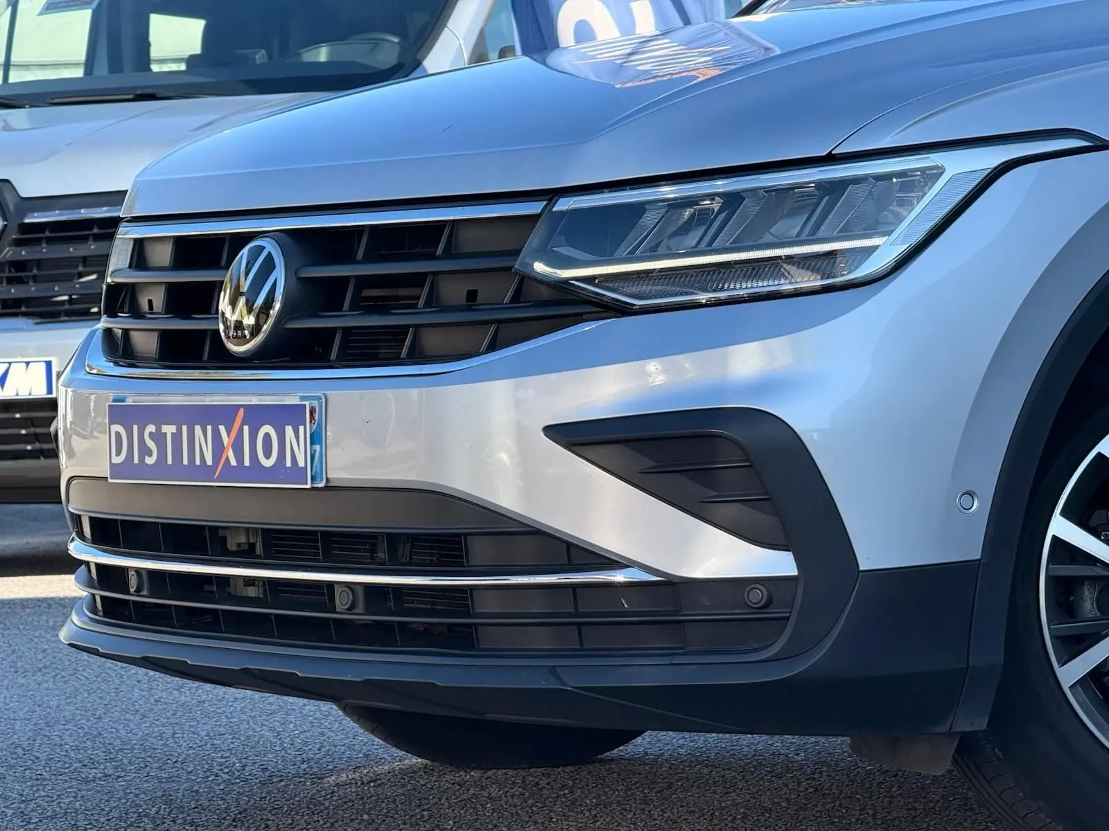 Vue 3/4 avant droit d'un Volkswagen Tiguan 2021 en reflet argent, mettant en valeur sa calandre noire et ses phares LED.