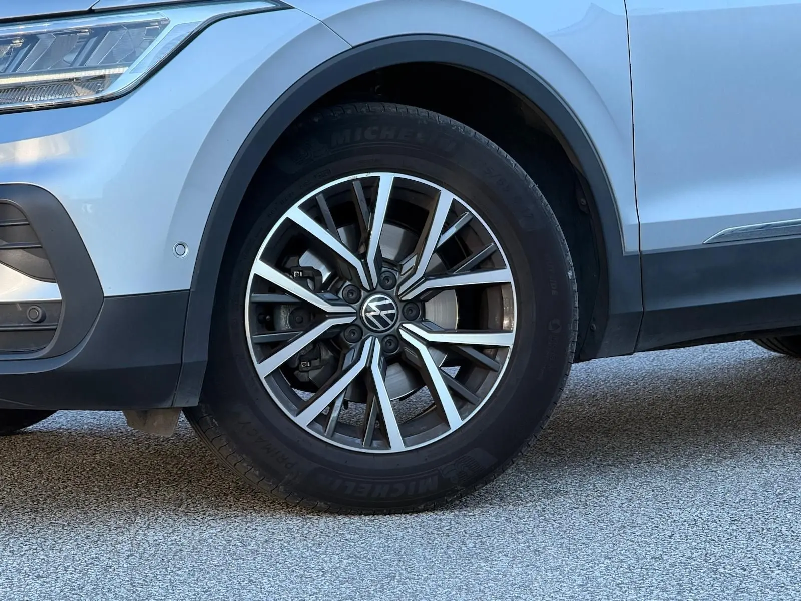 Gros plan sur la roue avant gauche d'un Volkswagen Tiguan 2021 reflet argent, avec jante alliage et logo VW visible.