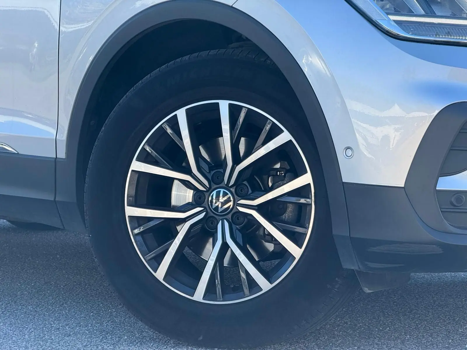 Gros plan sur la roue avant gauche du Volkswagen Tiguan 2021 en reflet argent avec jante alliage noire et argentée.