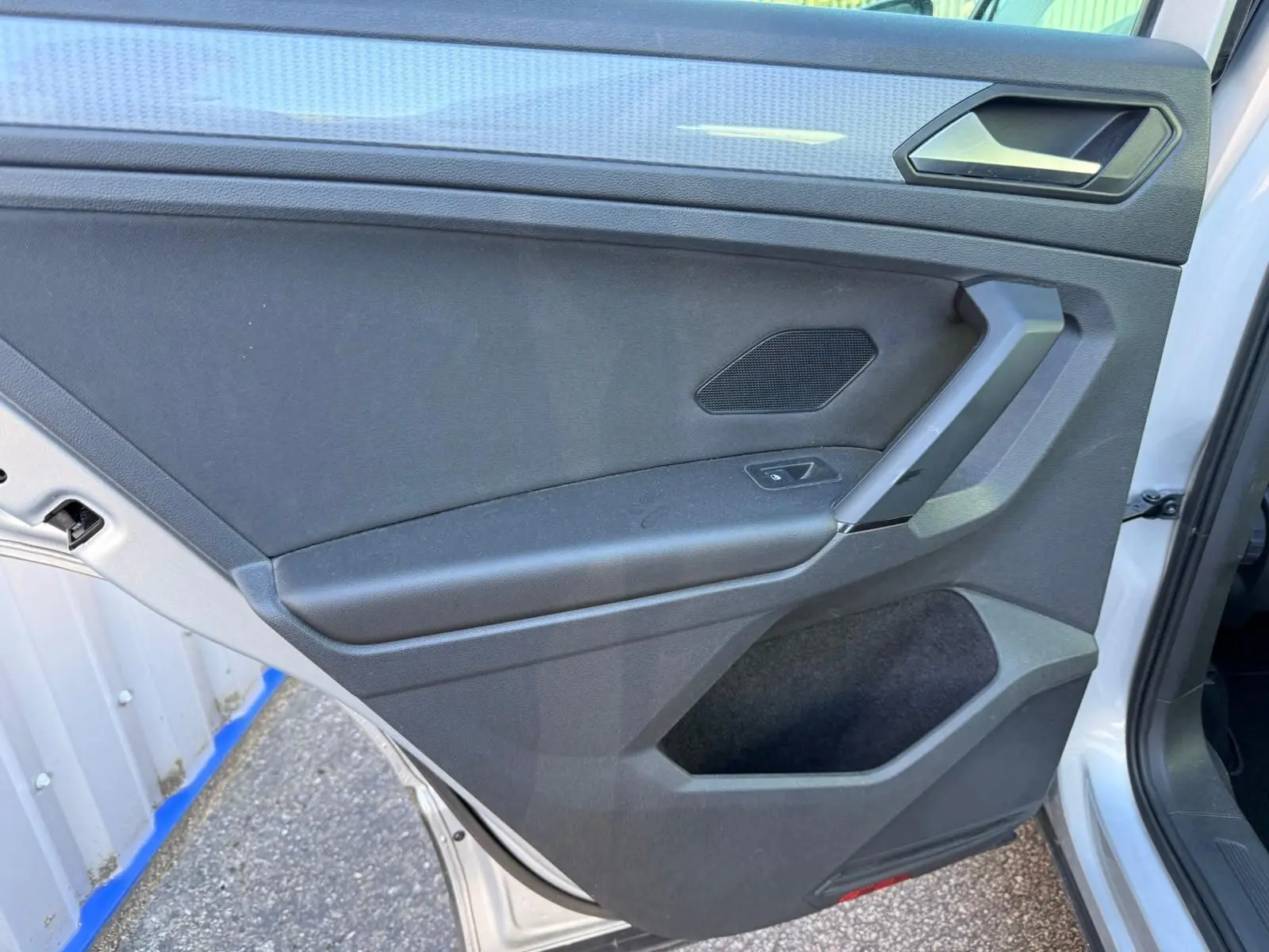 Porte arrière droite ouverte du Volkswagen Tiguan 1.5 TSI 150CH Life 2021 en reflet argent, intérieur noir avec poignée angulaire.