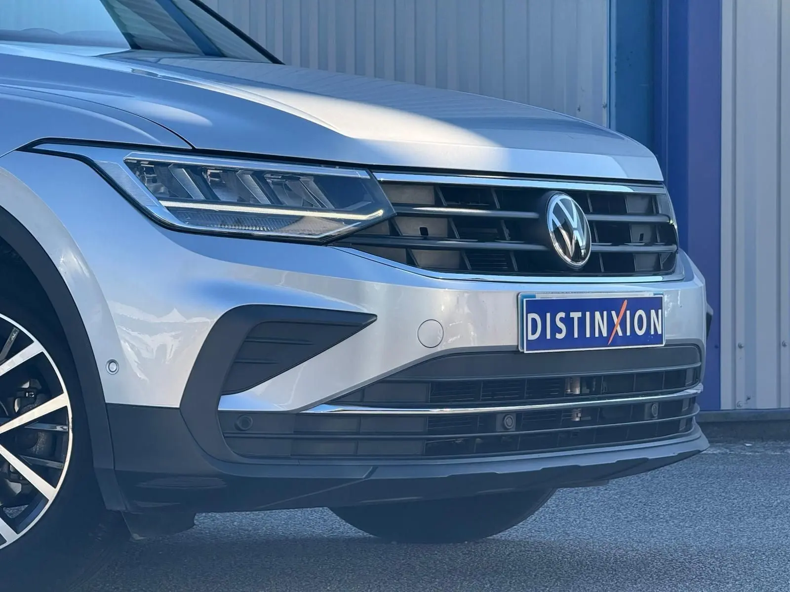 Vue 3/4 avant gauche d'un Volkswagen Tiguan 2021 couleur reflet argent avec calandre noire et logo VW visible.