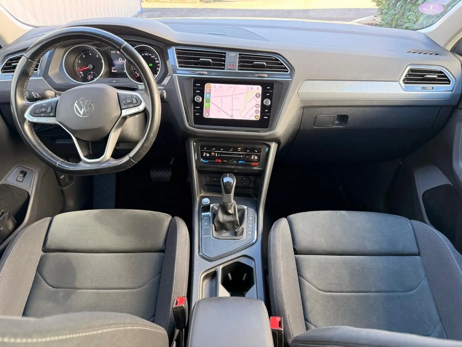 Vue intérieure avant du Volkswagen Tiguan 1.5 TSI 150CH LIFE DSG7 avec tableau de bord noir et écran tactile central affichant une carte.