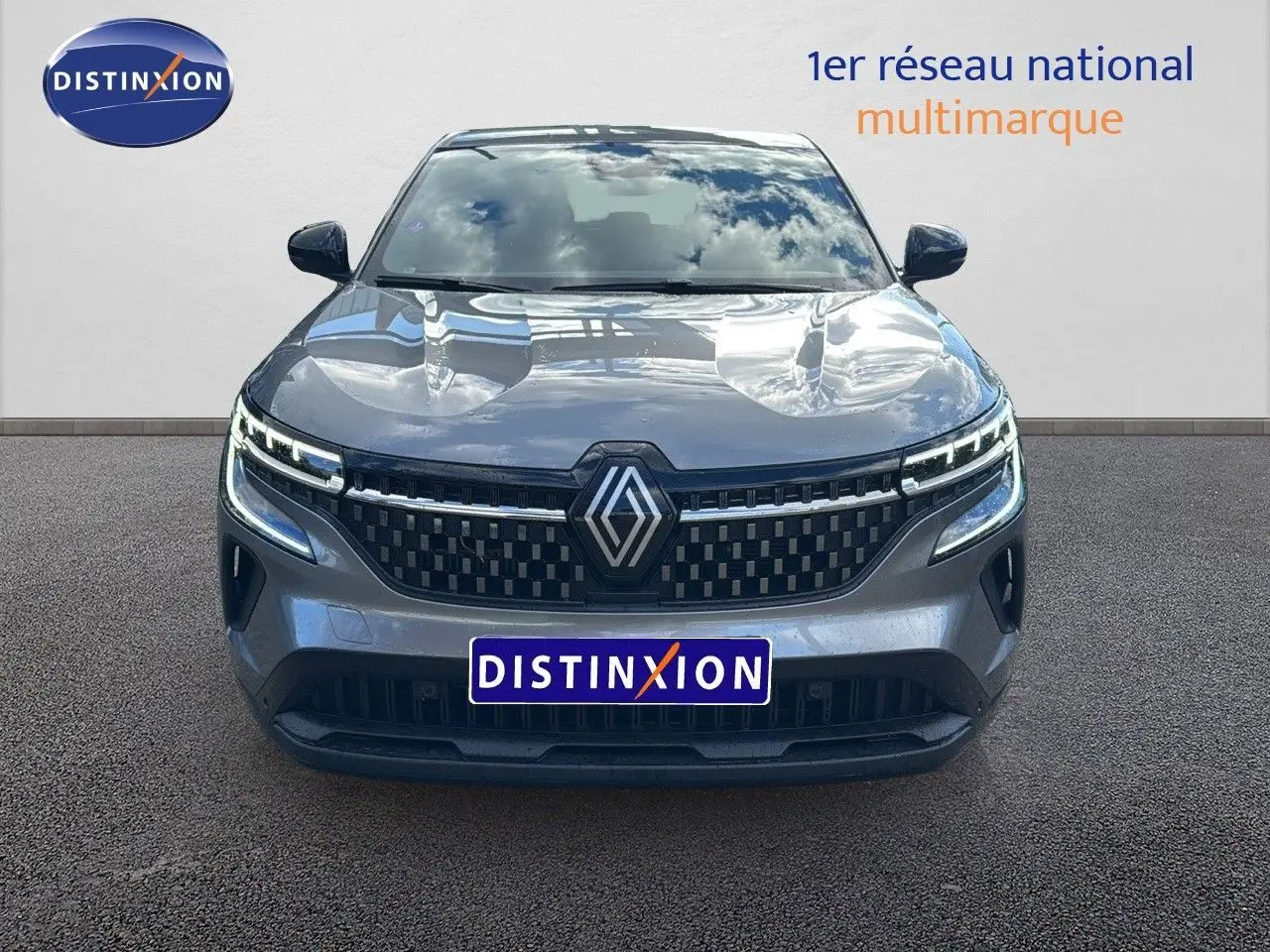 Vue frontale du Renault Austral gris schiste 2023 avec calandre à damier et feux LED distinctifs allumés.