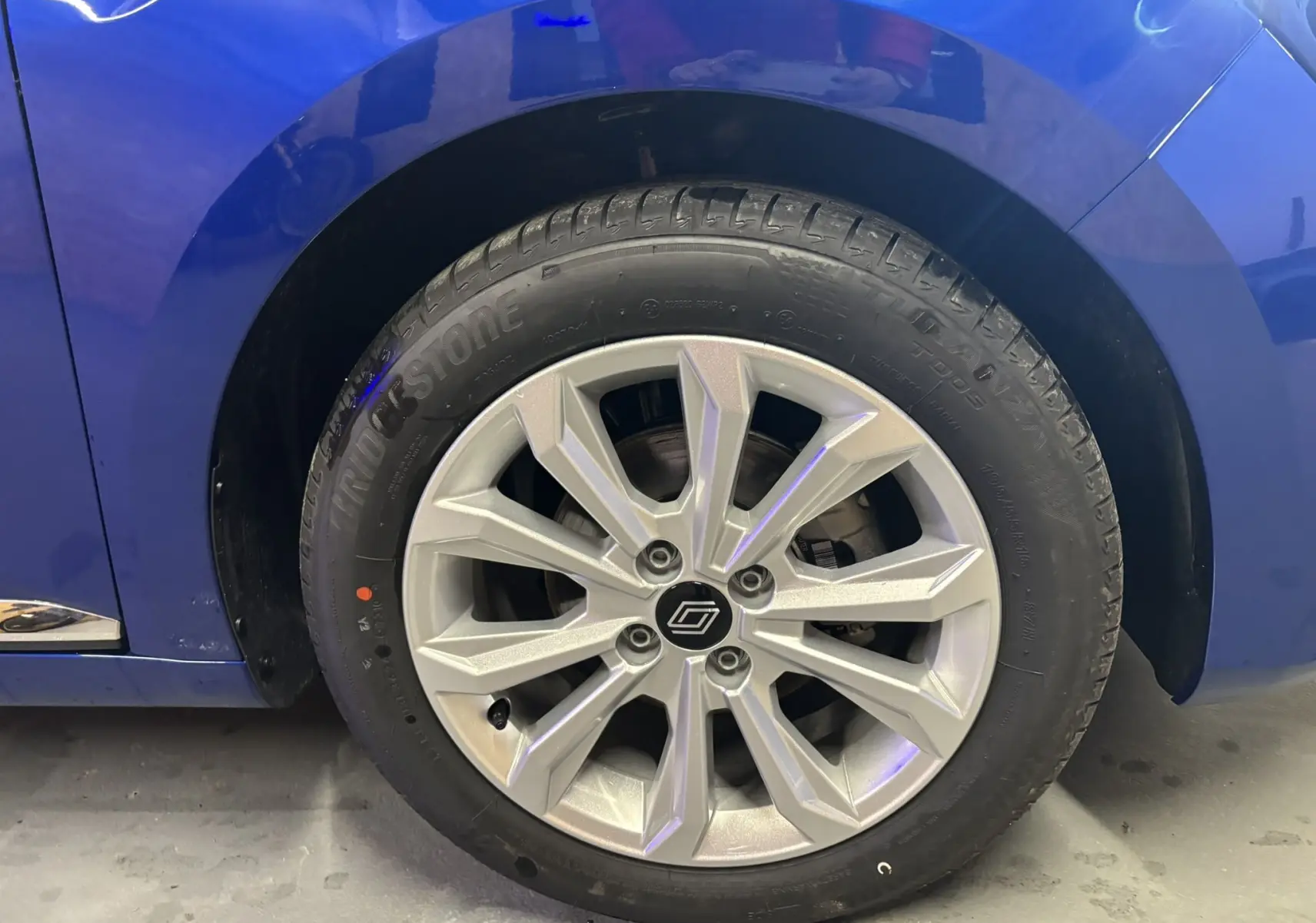 Gros plan sur la roue avant gauche de la Renault Clio TCE 90CH X-TRONIC Evolution 2024 en bleu Iron, jante argentée.