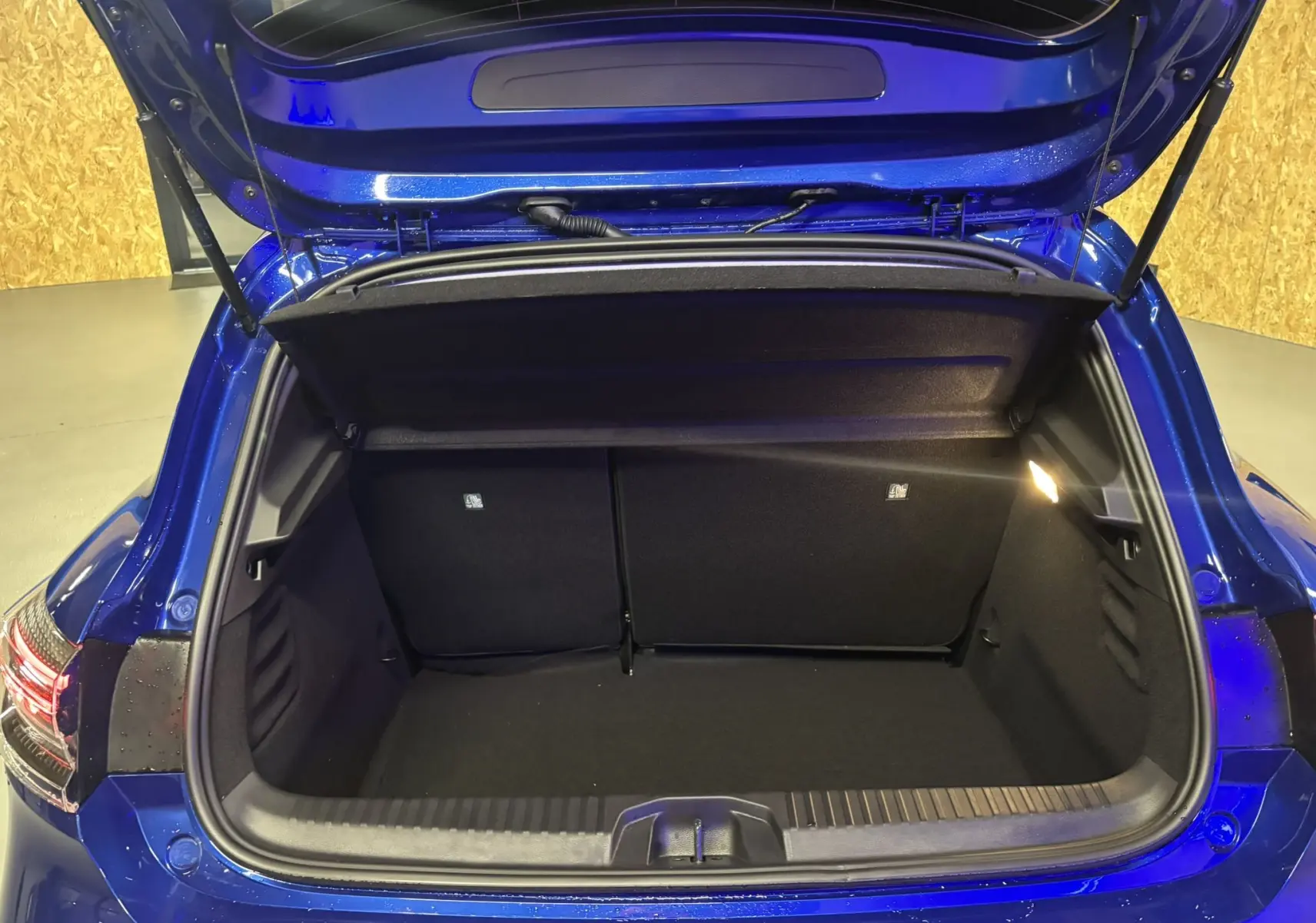 Coffre ouvert de la Renault Clio TCE 90CH X-TRONIC Evolution 2024 en bleu iron, vue arrière montrant l'espace de rangement vide.