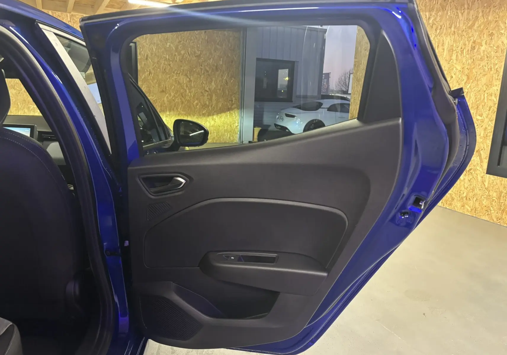 Porte arrière côté gauche ouverte d'une Renault Clio TCE 90CH X-TRONIC Evolution bleu Iron, intérieur tissu gris noir visible.