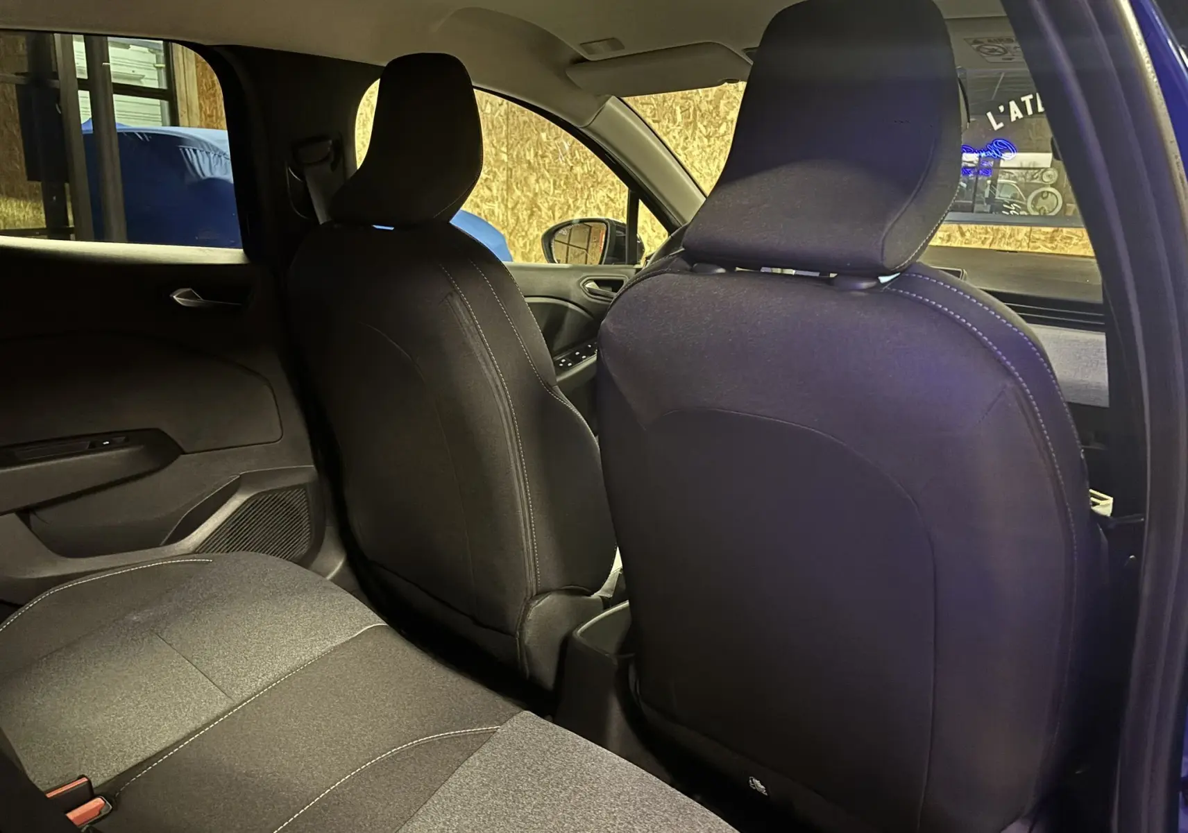 Vue intérieure arrière de la Renault Clio 2024 en tissu gris noir, montrant les dossiers des sièges avant et la banquette arrière.