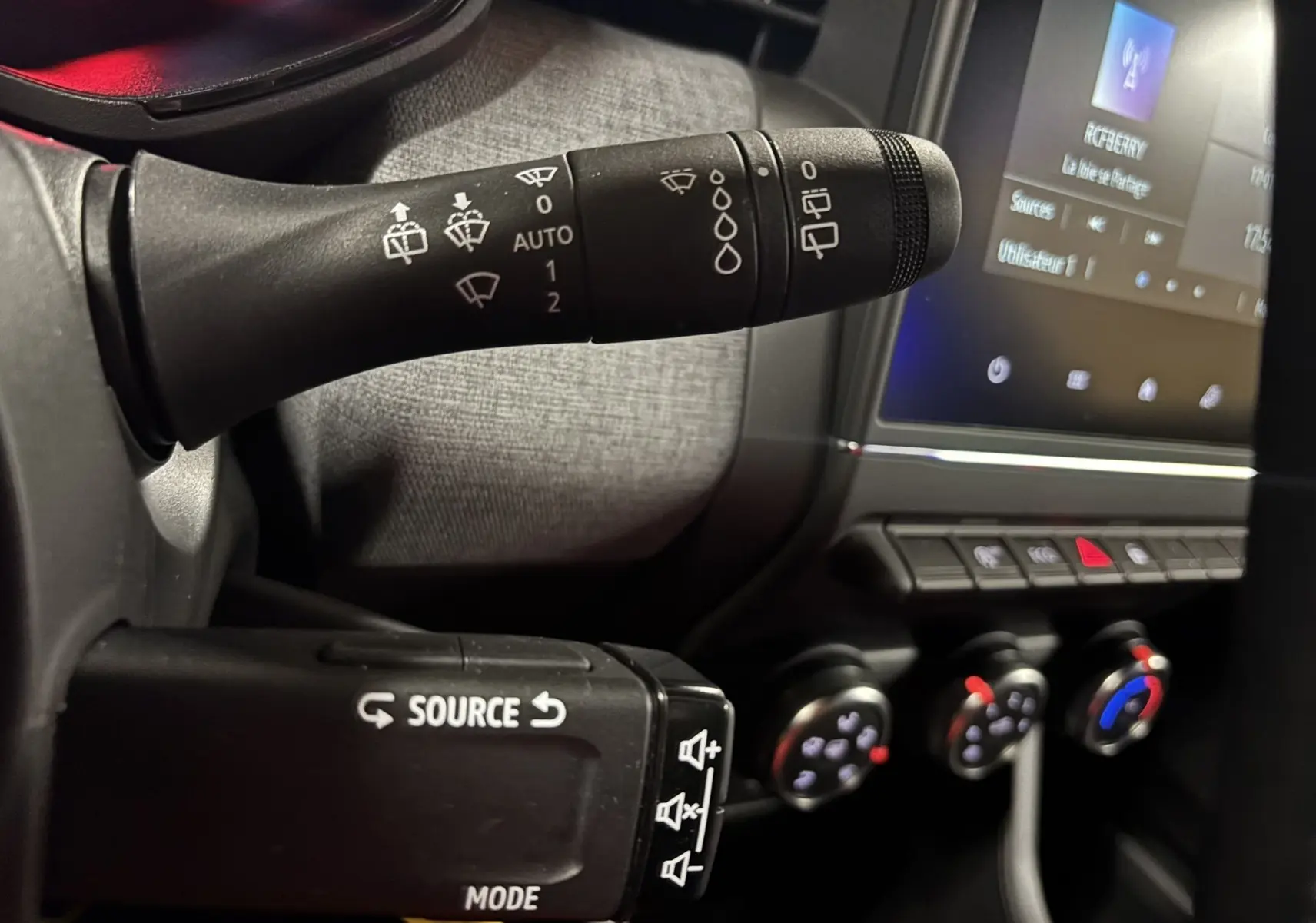 Gros plan sur les commandes au volant et la console centrale du Renault Clio TCe 90ch X-Tronic Evolution 2024, intérieur gris-noir.