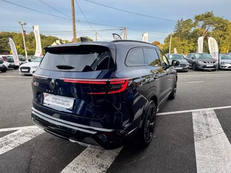 Vue 3/4 arrière droite d'un Renault Espace 2023 Bleu Nocturne avec feux arrière LED allumés sur parking.