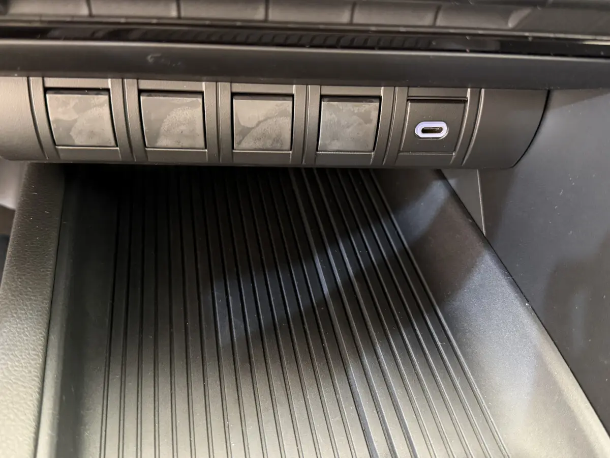 Gros plan sur la prise USB-C et les boutons au-dessus du rangement central du Toyota C-HR blanc 2024.