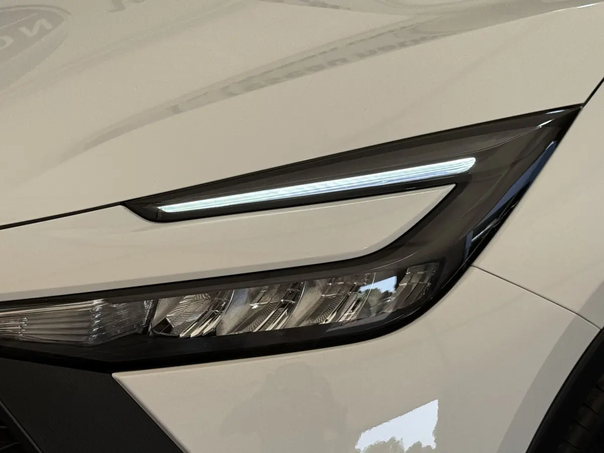 Gros plan sur le phare avant droit blanc du Toyota C-HR 1.8 Hybride 140 Dynamic avec LED fine et design anguleux.