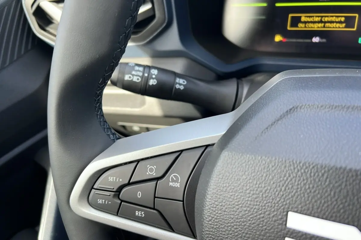Gros plan sur le volant cuir noir côté gauche du Dacia Bigster 2026 avec commandes intégrées et affichage digital partiel.