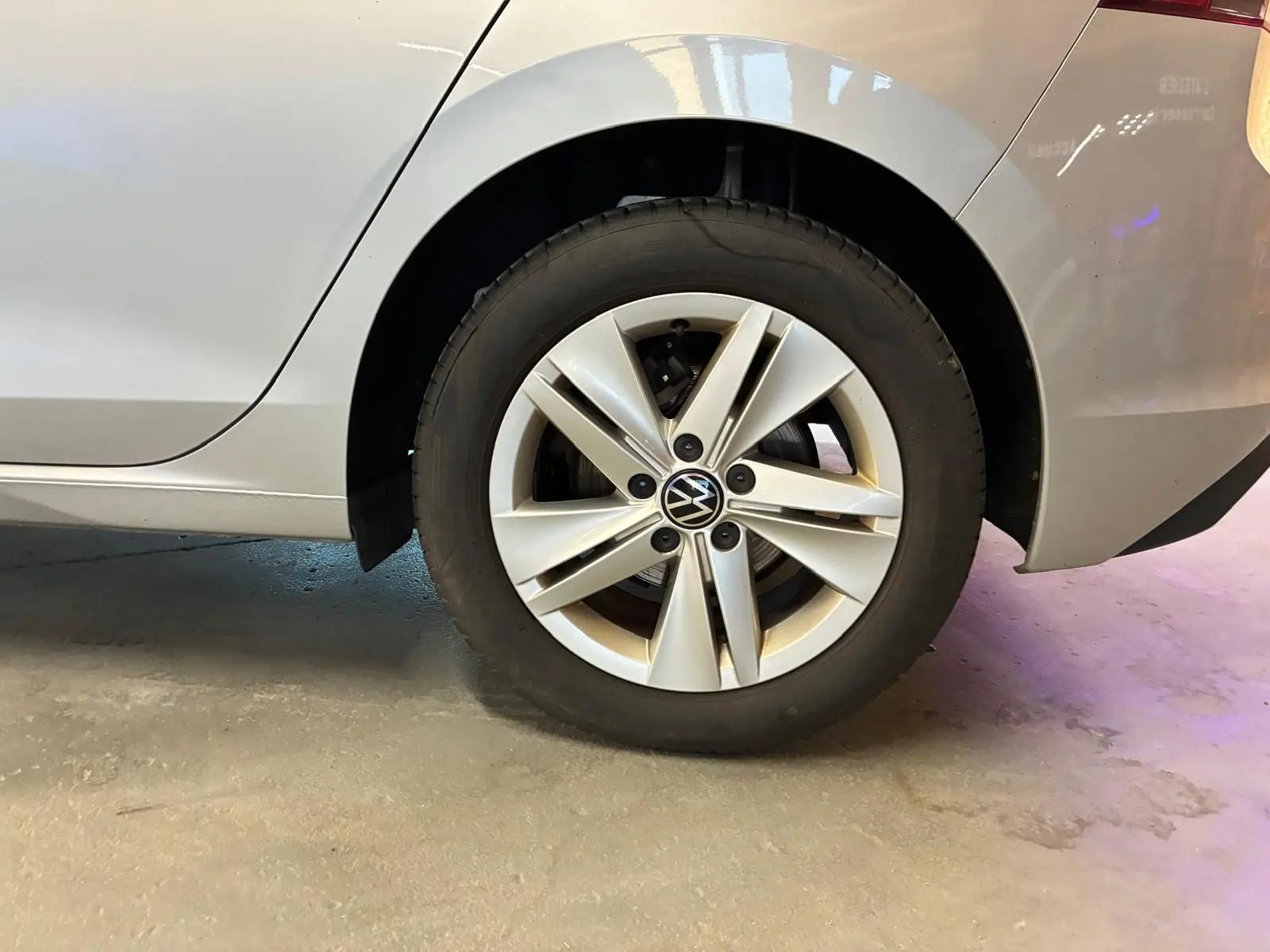 Gros plan sur la roue arrière droite d'une Volkswagen Golf gris clair 2023, jante alliage à cinq branches doubles.