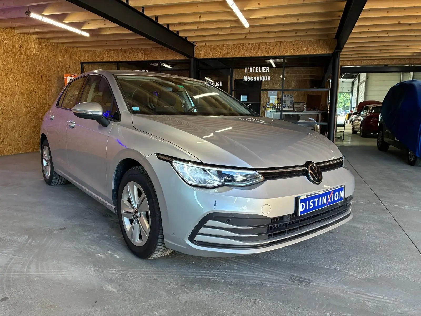 Volkswagen Golf 1.0 eTSI gris clair vue 3/4 avant droit dans un garage avec éclairage intérieur.