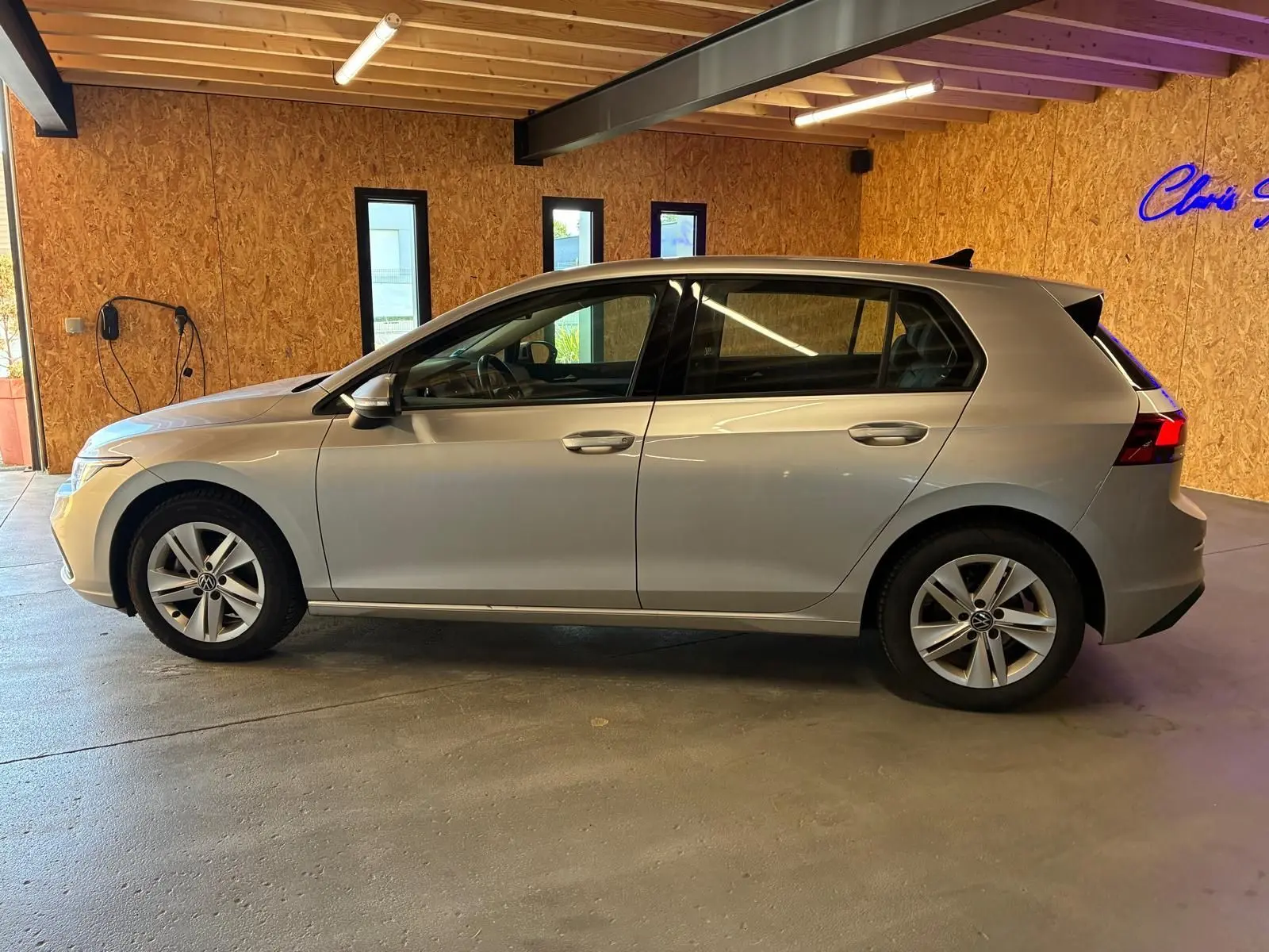 Vue de profil côté gauche d'une Volkswagen Golf gris clair 2023, version 1.0 eTSI 110 DSG7 LIFE PLUS, en intérieur.