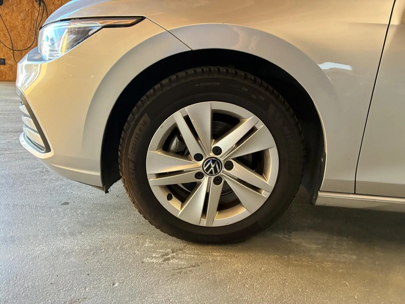 Gros plan sur la roue avant gauche d’une Volkswagen Golf gris clair 2023, avec jante alliage à cinq branches.