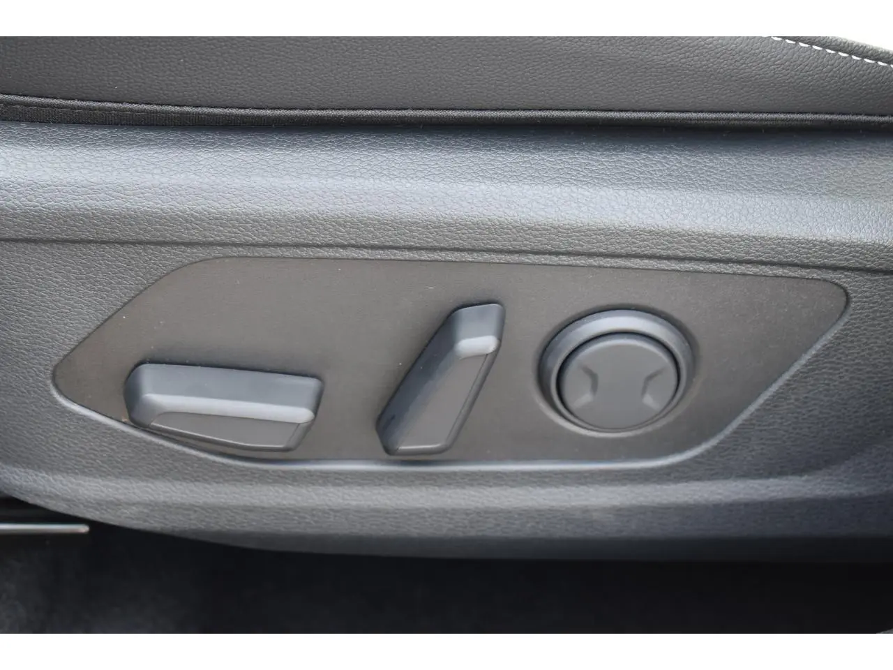 Gros plan sur les commandes électriques de réglage du siège avant du KIA SPORTAGE gris hybride 2026.