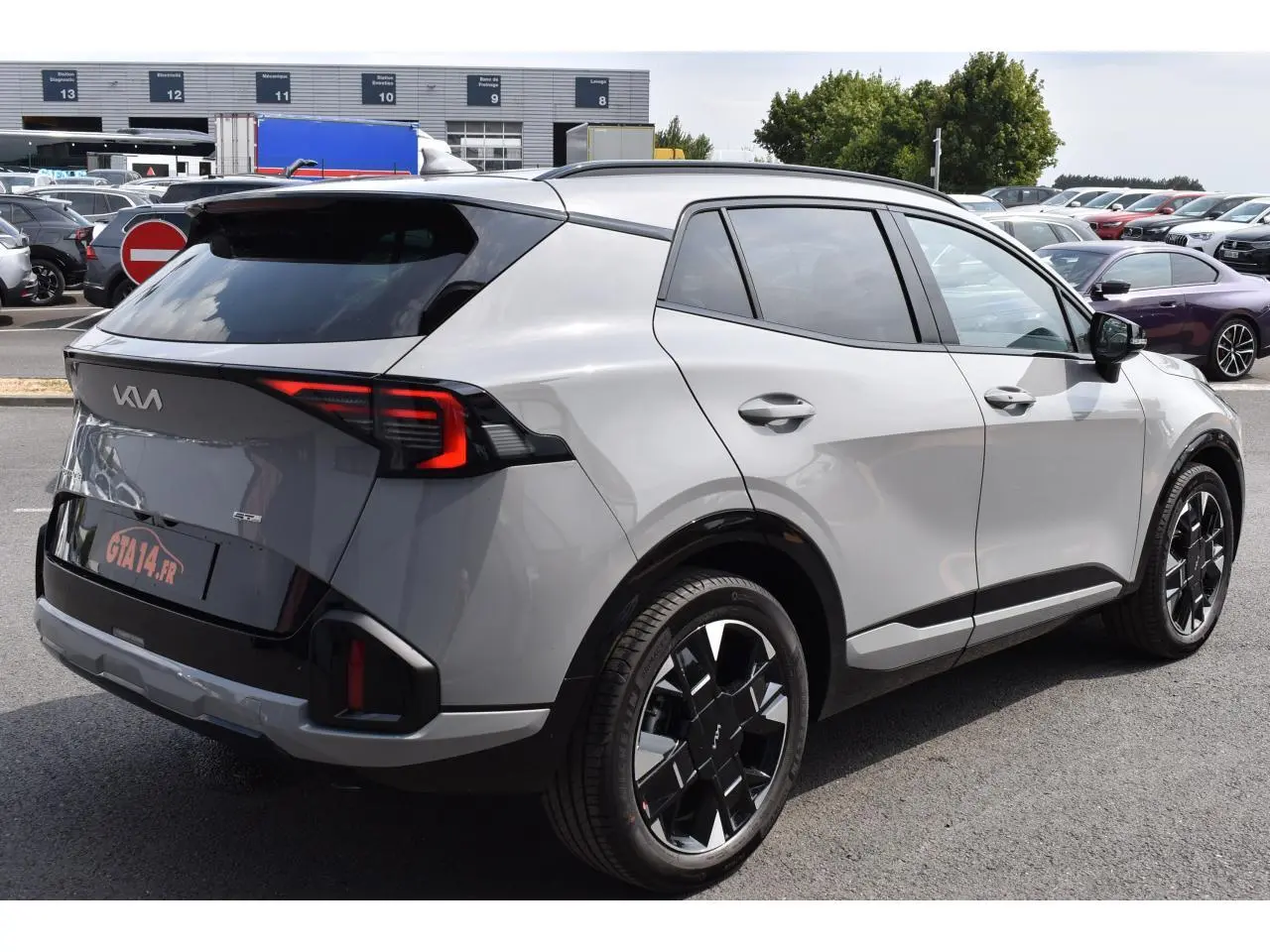 Vue 3/4 arrière droite du KIA Sportage hybride gris avec jantes noires et feux arrière LED distinctifs.