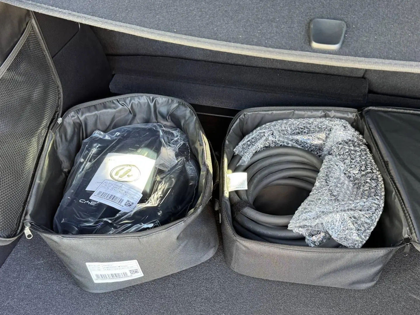 Coffre ouvert d'un BYD SEAL U 1.5 DM-i 324ch Design AWD 2026, montrant les câbles de recharge rangés dans des sacs noirs.