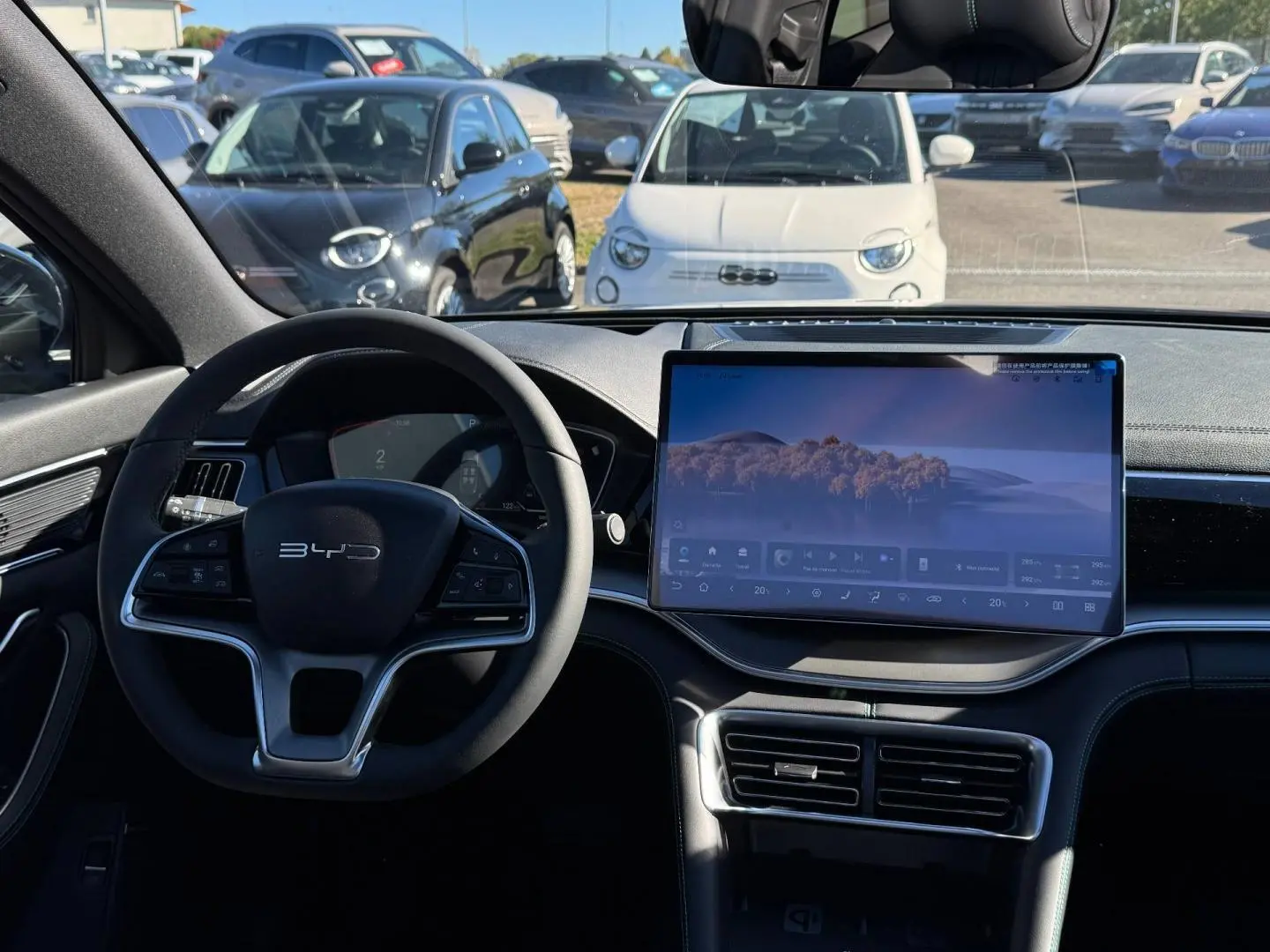 Vue intérieure avant du BYD SEAL U 1.5 DM-i 324ch Design AWD avec volant multifonction et grand écran tactile central.