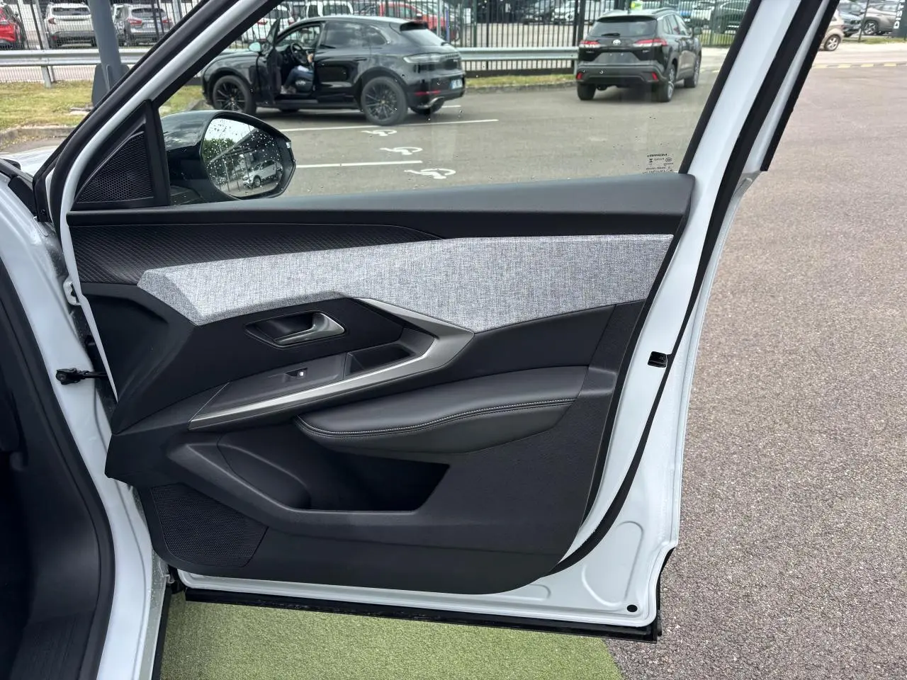 Porte avant gauche ouverte d'un Peugeot 3008 blanc Okenite, montrant le décor tissu gris et noir avec surpiqûres blanches.
