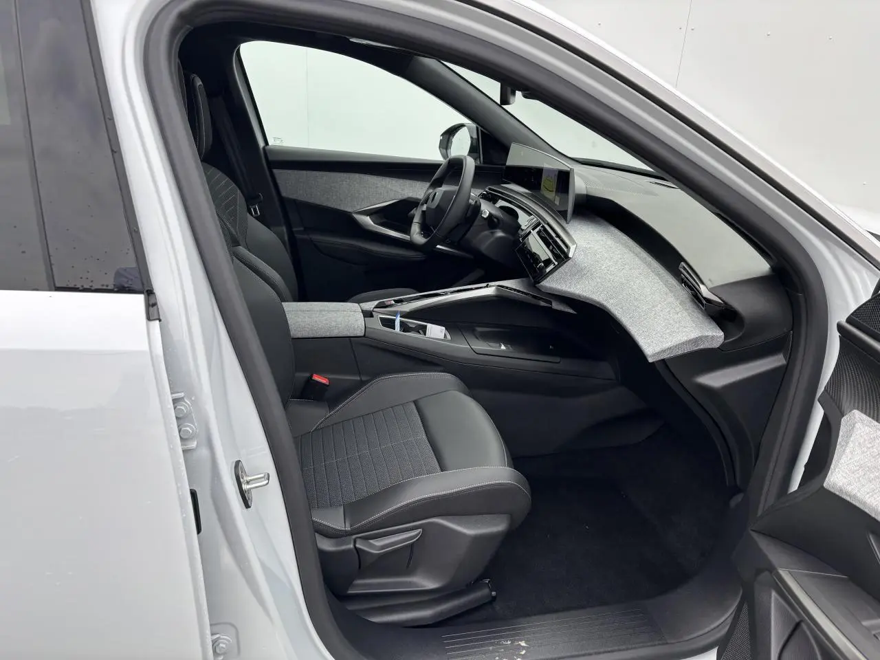 Intérieur côté conducteur du Peugeot 3008 blanc Okenite 2024, avec tableau de bord tissu gris et sièges noirs.
