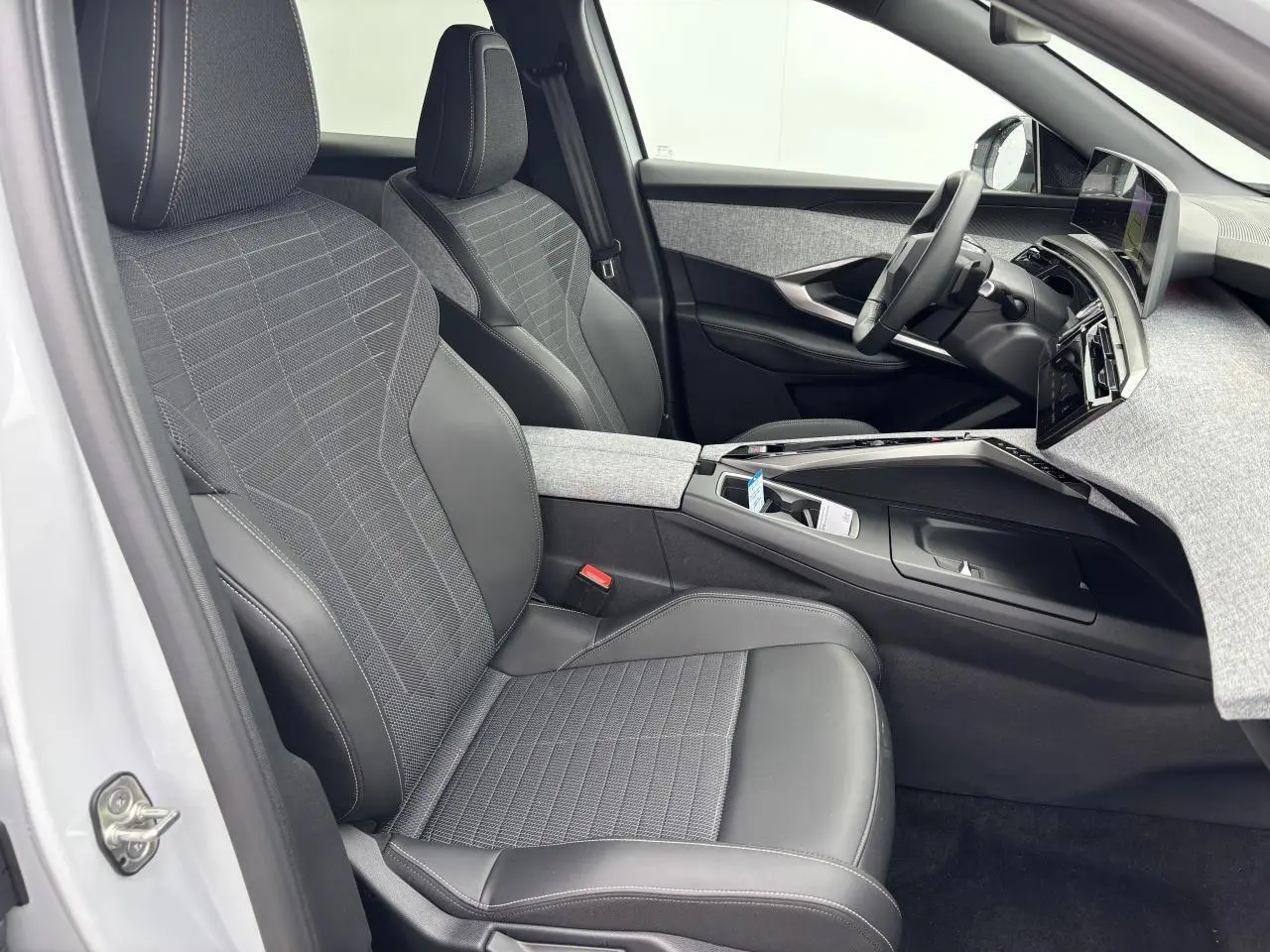 Intérieur avant droit du Peugeot 3008 blanc Okenite 2024 avec sièges tissu noir et tableau de bord gris chiné.