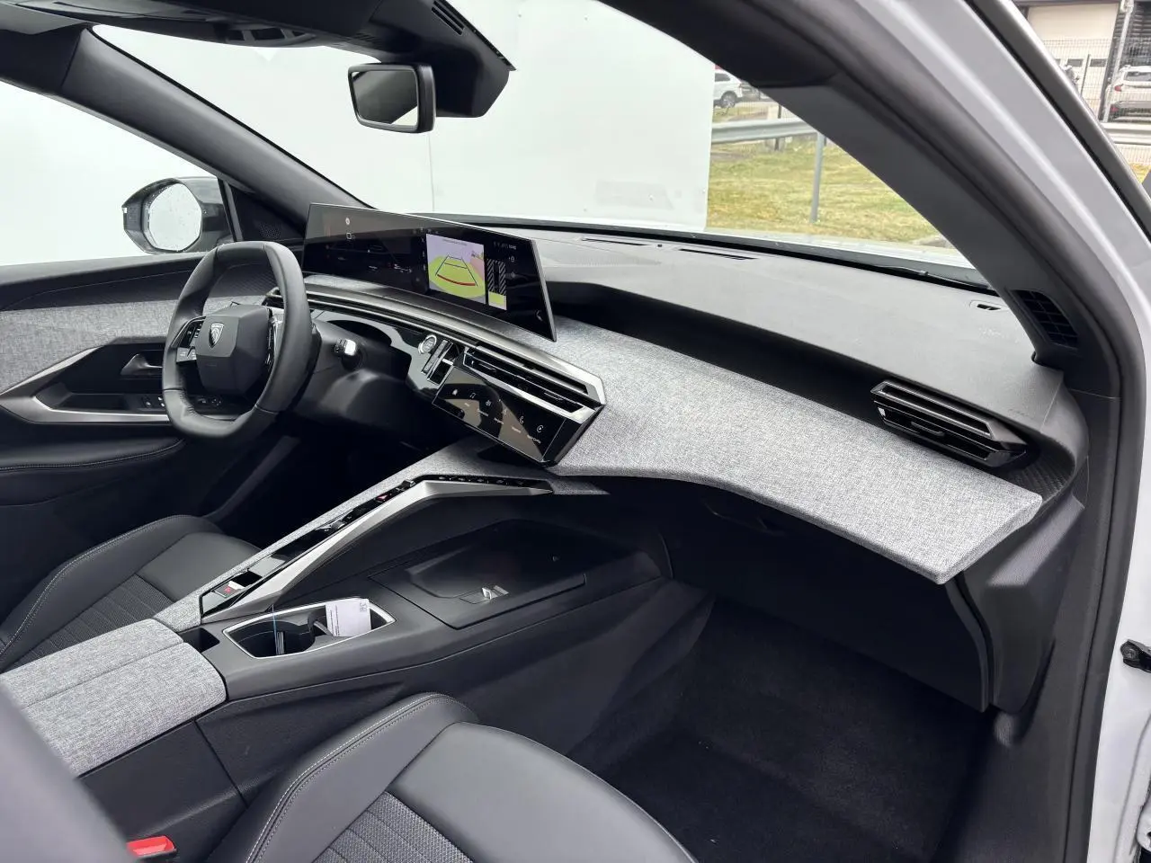 Intérieur avant droit du Peugeot 3008 blanc Okenite 2024, tableau de bord tissu gris clair et écran incurvé flottant.