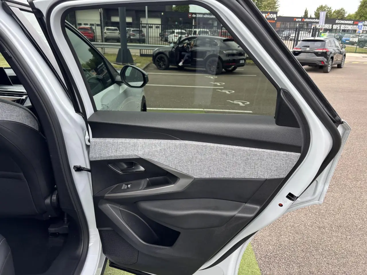 Vue intérieure de la porte arrière gauche blanche du Peugeot 3008 III 1.2 HYBRID 136 Allure avec décor tissu gris et noir.