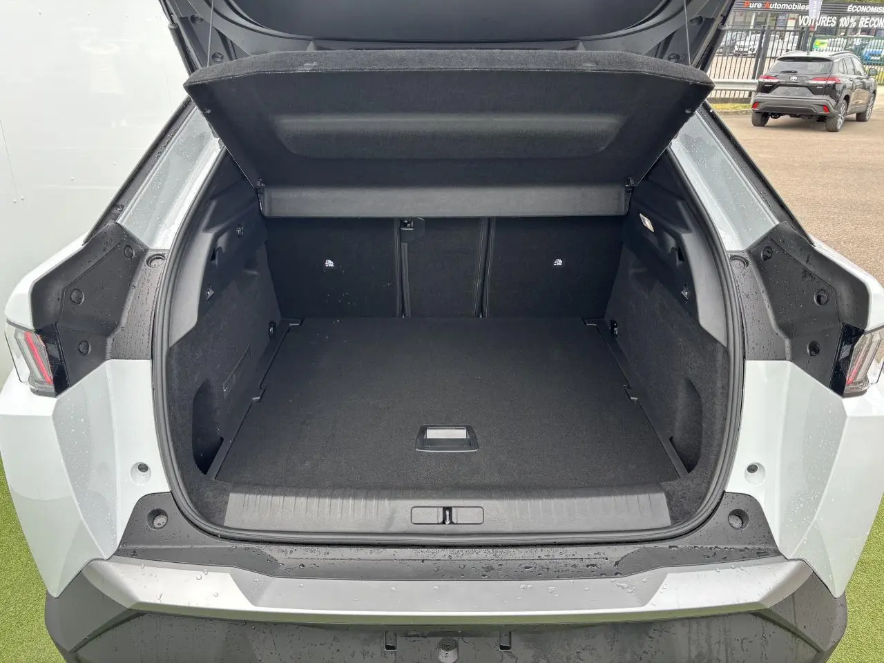 Coffre ouvert vu de l'arrière d'un Peugeot 3008 blanc Okenite 2024, avec intérieur noir et feux arrière LED visibles.