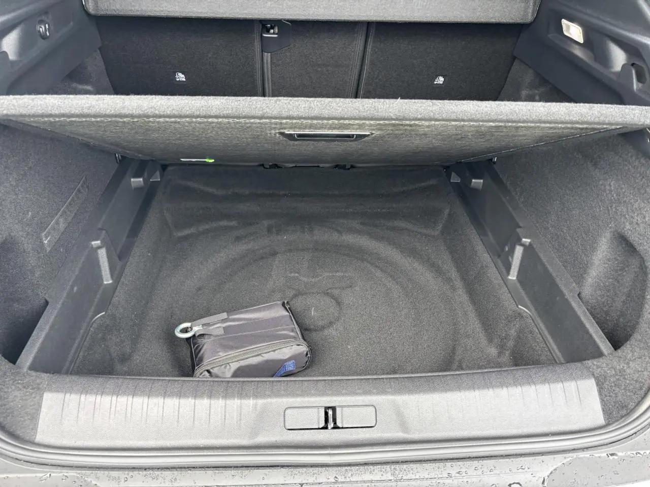 Coffre ouvert du Peugeot 3008 blanc Okenite 2024, montrant un espace de rangement vide avec un petit sac noir.